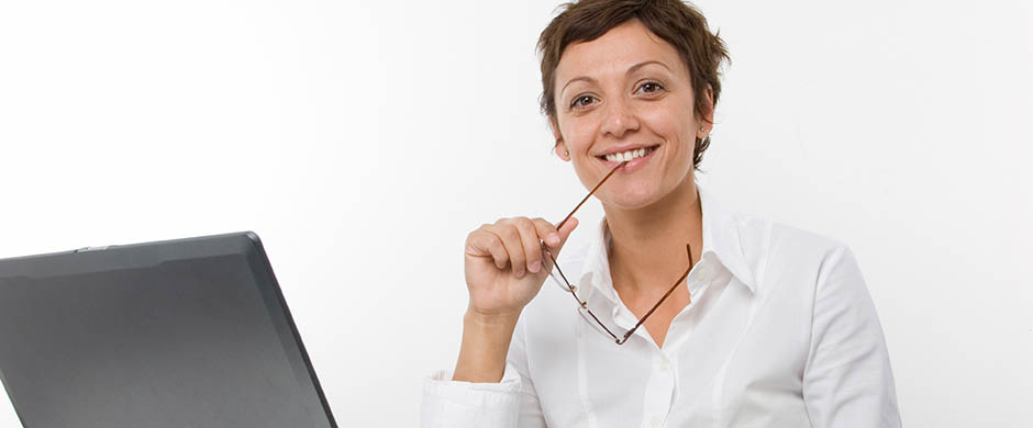 Eine lächelnde Frau sitzt hinter ihrem Computer