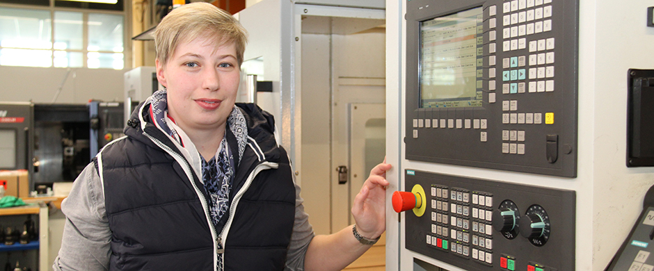 Eine junge Berufseinsteigerin bedient eine CNC-Zerspanungsmaschine