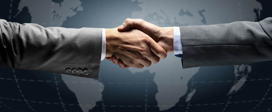 Ein Handschlag zweier Geschäftsmänner, im Hintergrund die Weltkugel