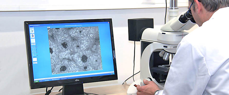 Ein Werkstoffprüfer untersucht einen Werkstoff unter dem Mikroskop