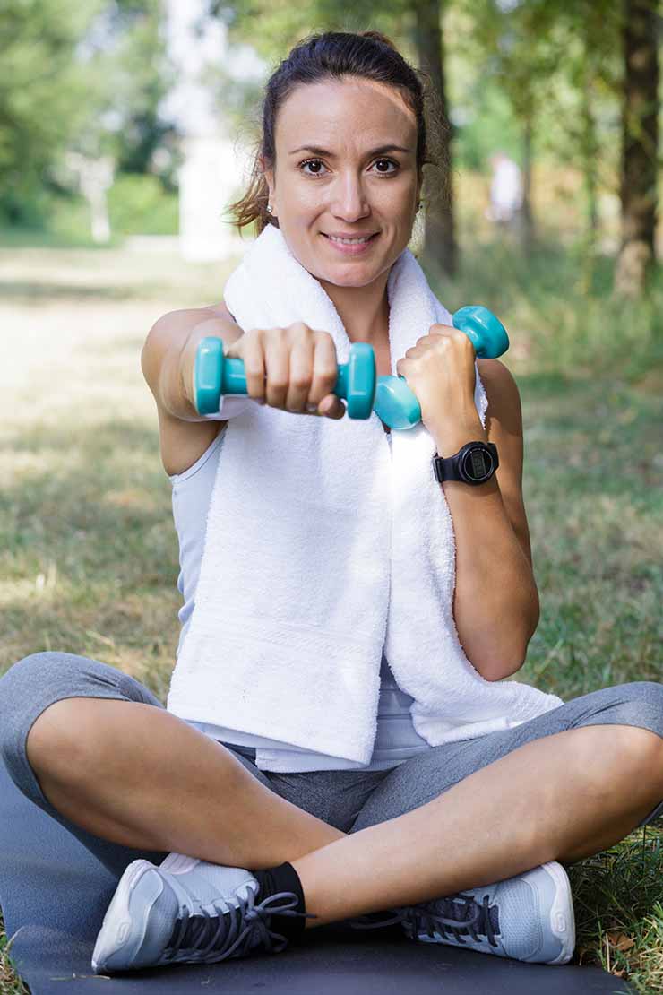 Frau übt draußen mit Hanteln